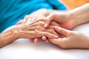 A caregiver holds a person's hand